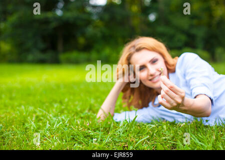 Bella sano giovane donna sdraiata e rilassante sull'erba verde Foto Stock