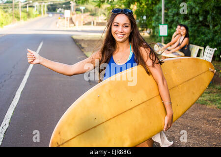 Pacific Islander surfer escursioni del sollevatore sulla strada rurale Foto Stock