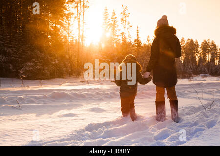 La madre e il figlio a piedi nei boschi innevati clearing Foto Stock