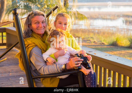 Nonna caucasica e nipoti usando il binocolo sul portico Foto Stock