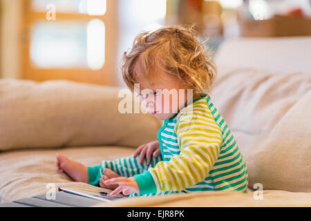 Caucasian baby boy utilizzando digitale compressa sul divano Foto Stock