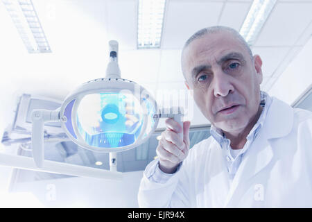 Dentista ispanica tenendo la lampada in ufficio Foto Stock