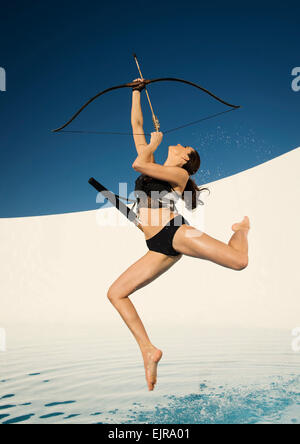 La donna caucasica mirando arco e frecce Foto Stock