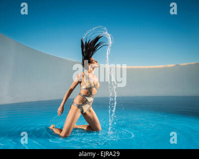 La donna caucasica tossing capelli sulla piscina Foto Stock