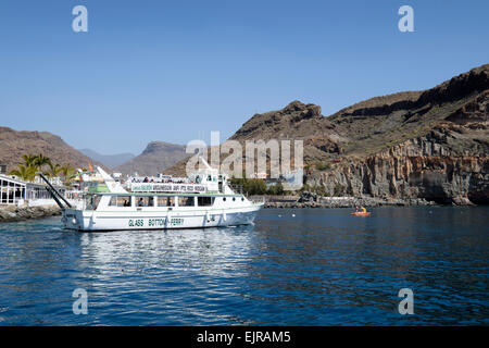 Un fondo di vetro vele di traghetto da Puerto de Mogan Harbour, Gran Canaria, Spagna Foto Stock