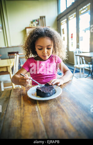 Razza mista ragazza di mangiare il dessert in cafe Foto Stock