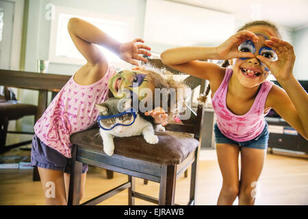 Razza mista sorelle giocando con la faccia di vernice e googly occhi Foto Stock