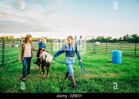 Tre generazioni di donne caucasiche passeggiate a cavallo in miniatura in agriturismo Foto Stock