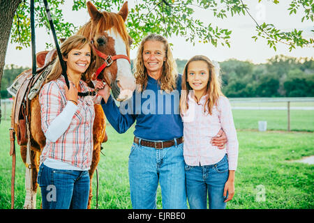 Tre generazioni di donne caucasiche in piedi vicino a cavallo in agriturismo Foto Stock