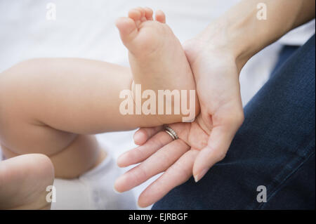 Close up di razza mista madre tenendo il piede del bambino Foto Stock