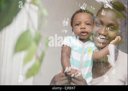 Nero madre e figlio a guardare fuori dalla finestra Foto Stock