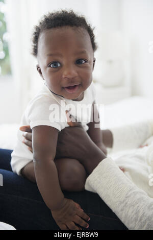 Close up di madre holding nero sorridente baby boy Foto Stock