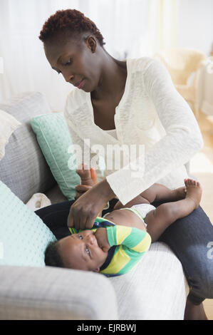 Close up della madre nera cambiando pannolino del bambino Foto Stock