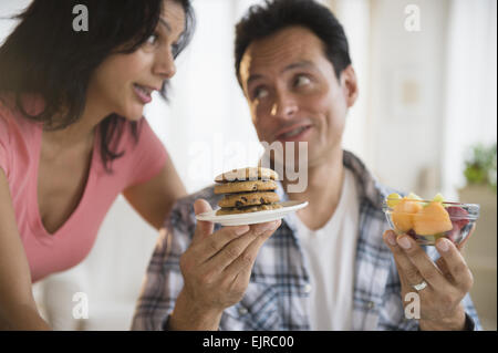 Giovane scegliendo tra un sano e malsano spuntini Foto Stock