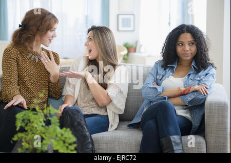 La chat donne ignorando sconvolto amico sul divano Foto Stock