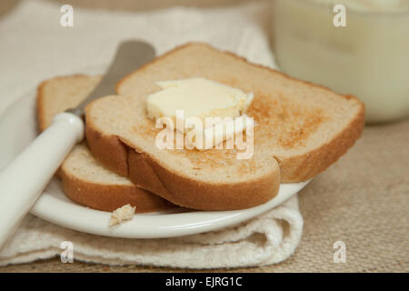 Due fette di pane tostato poggiano su una crema colorata; piastra di Coltello per burro posto a lato del pane tostato Foto Stock