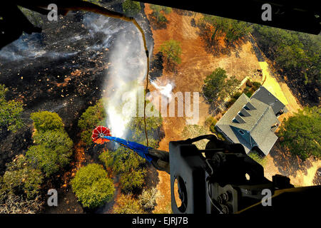 I Bambi Bucket attaccato a un CH-47 elicottero dall'2-149th, Texas Guardia nazionale, discariche di acqua su un tripudio quasi proprietà. Texas National Guard per equipaggi lanciato al di fuori dell'esercito di Austin Aviation Facility per la lotta contro gli incendi selvatici che minacciano le case e proprietà vicino Bastrop, Texas, 6 settembre 2011. Il personale Sgt. Malcolm McClendon Foto Stock