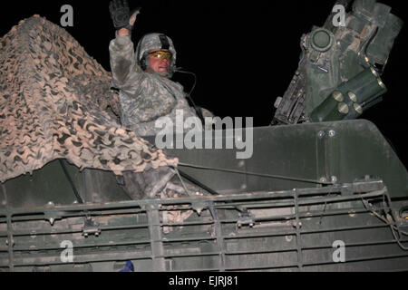 Un soldato con la quarta Stryker Brigade Combat Team, seconda divisione di fanteria onde come lui e i suoi compagni di Strykers roll attraverso il boarder dall'Iraq in Kuwait nelle prime ore del mattino del 19 agosto. Il 4/2 convogliato i propri veicoli fuori dall'Iraq dopo un anno-lungo tour vi, portando a livelli di truppe nel paese più vicino al contrassegno di 50.000. Il primo teatro supporto comando ha svolto un ruolo importante nella sottrazione del 4/2 fornendo i servizi necessari per i soldati per pulire e spedire le loro attrezzature per gli Stati Uniti. Foto Stock