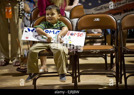 Jesse Mead figlio di U.S. Army Sgt. 1. Classe Korey Mead detiene un welcome home segno per il suo papà durante il XXV divisione di fanteria sede cerimonia di reimpiego a Wheeler Army Airfield in Wahiawa, Hawaii, dic. 18. Il venticinquesimo ID quartier generale è stato l'ultimo la divisione ha sede sotto le forze degli Stati Uniti a lasciare l'Iraq. Foto Stock