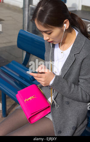 Attraente giovane donna seduta su un banco di lavoro sms sul telefono Foto Stock