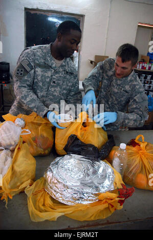 Sgt. Marcus Wright, nativo di Jacksonville, Florida, e SPC. Joe Kunkel, nativo di Webster, Massachusetts, disimballare il pasto tradizionale è servita a circa 25 detenuti presso il detenuto area di contenimento allegato su Camp Taji, a nord-ovest di Bagdad, 1 ottobre, 2008. Una tradizionale festa che è stato preparato per i detenuti nella celebrazione di Eid al-Fitr. Entrambi Wright e Kunkel sono funzionari di polizia militare assegnato alla sede centrale e sede della società 3, truppe speciali Battaglione multinazionale - Divisione di Baghdad. Foto Stock