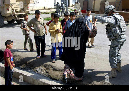 Il personale Sgt. Jon Anderstrom aiuta un'anziana donna irachena attraversare un cordolo mentre si incontra con negozio locale proprietari al mercato di cedro, Mosul, Iraq, Sett. 21, 2008. Anderstrom è assegnato alla società C, 1° Battaglione, 8° Reggimento di Fanteria. Pfc. Sarah De Boise Foto Stock