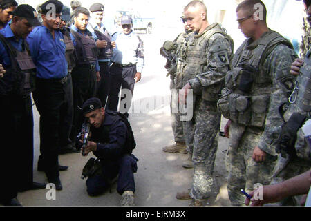 Sgt. Jay Gillam ed esercito Sgt. Spencer Arnold tenere un occhio vigile su un iracheno funzionario di polizia come egli dimostra il suo inginocchiarsi tecnica di cottura durante il corso di formazione a Baghdad del distretto Kadhimiyah, Sett. 26, 2008. Stati Uniti Foto dell'esercito Foto Stock