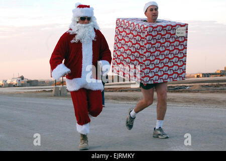 Sgt. Anthony Ward, vestita di Santa suit e 1Lt. Philip Vrska, nel pacchetto di Natale, porterà un po' di allegria natalizia a un 5K "Jingle" Race sponsorizzata su Camp Ramadi, Iraq, Dic 20, 2008. Mentre la coppia di festa non ha posto nel campo di 64 hanno fatto di completare l'intera esecuzione in costume. Sgt. Emily Suhr Foto Stock