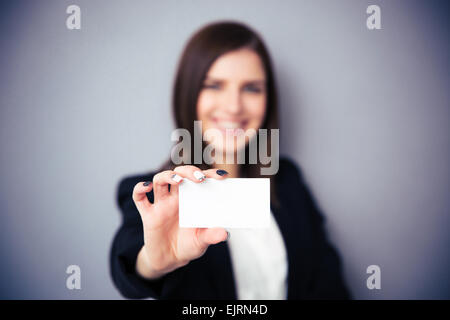 Donna che mantiene la scheda in bianco su sfondo grigio. Focus su scheda Foto Stock