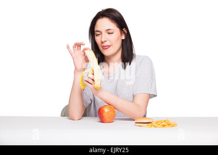 Naturale donna espressiva giocando con patatine fritte, avendo di fronte junk e cibo sano, isolato su bianco Foto Stock