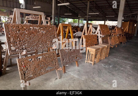 Legno intagliato in teak traforature pannelli in corrispondenza di una parete in legno fabbrica, Chiang Mai, Thailandia del Nord Foto Stock