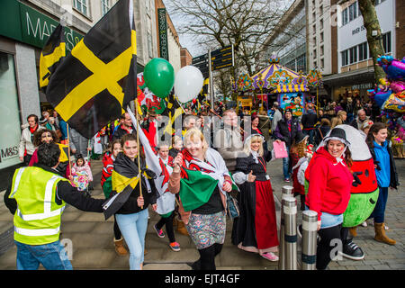 Popolo gallese sventolando bandiere e striscioni marciando attraverso le strade di prendere parte ad "AberDewi' - giorno di San Davide patrono celebrazioni a Swansea Wales, Regno Unito Foto Stock