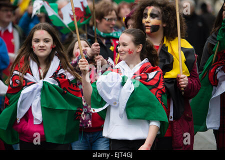 Popolo gallese sventolando bandiere e striscioni marciando attraverso le strade di prendere parte ad "AberDewi' - giorno di San Davide patrono celebrazioni a Swansea Wales, Regno Unito Foto Stock