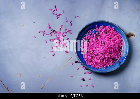 Non cotte riso rosa blu su piastra in ceramica su metallo grigio superficie. Vista dall'alto. Foto Stock