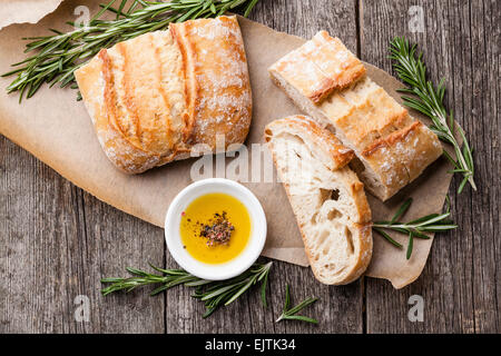 Fette di pane Ciabatta e olio extra vergine di oliva su sfondo di legno Foto Stock