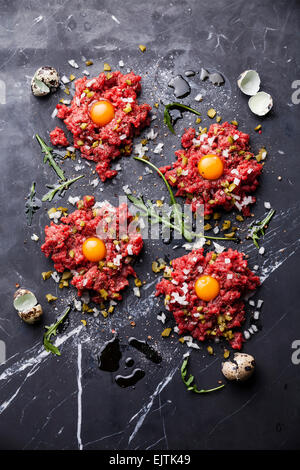 Tartare di manzo con cetriolo sottaceto e cipolla fresca sul marmo scuro dello sfondo Foto Stock