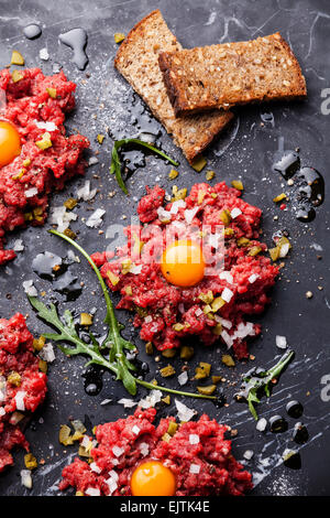 Tartare di manzo con toast fresco sul marmo scuro dello sfondo Foto Stock