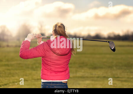 Giocatore di golf femminile osservando il suo rigido dal raccordo a t dopo aver effettuato una corsa fissando lungo il fairway Foto Stock