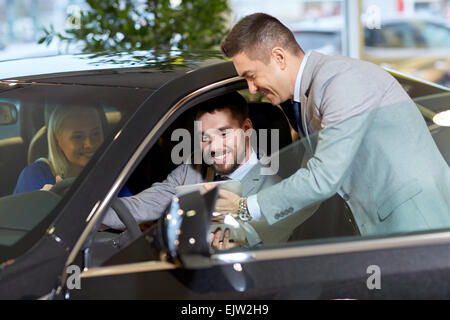 Coppia felice con il rivenditore di auto in auto show o salon Foto Stock