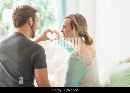 Vista posteriore del giovane messa a forma di cuore con le mani Foto Stock