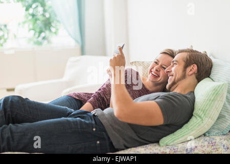 Sorridente giovane sdraiato sul letto e con tavoletta digitale Foto Stock