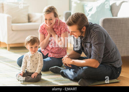 Genitori felici seduta con piccolo figlio (2-3 anni) sul pavimento Foto Stock
