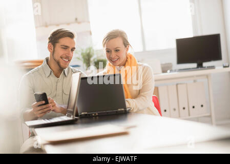 Giovane uomo e donna che lavorano insieme con il computer portatile in ufficio Foto Stock