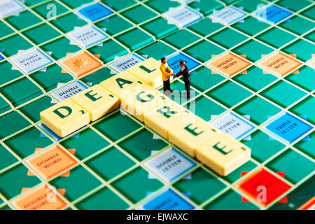 D'accordo trattare il tremolio delle mani Mani di legame di tenuta colleghi accordo le parole usando piastrelle scrabble per illustrare l'ortografia compitare Foto Stock