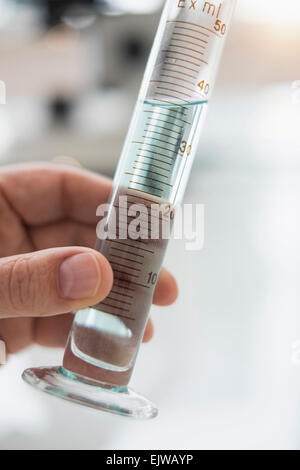 Stretta di mano d'uomo tenuta tubo di prova con il liquido Foto Stock