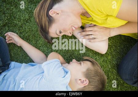 Madre e figlio (6-7) rilassante sull'erba Foto Stock