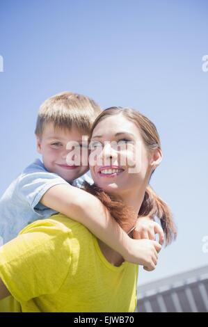 Madre dando il suo figlio (6-7) piggyback ride Foto Stock