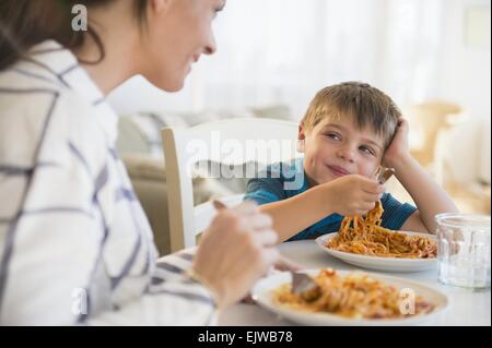 Madre e figlio (6-7) mangiare spaghetti Foto Stock