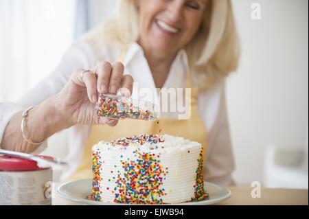 Donna senior di decorare la torta Foto Stock