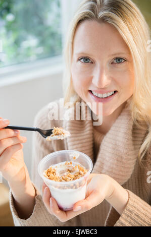 Ritratto di donna di mangiare yogurt con cereali Foto Stock